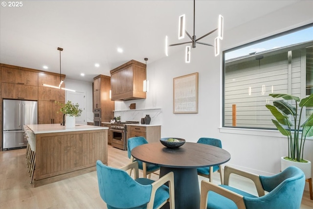 kitchen with light countertops, light wood-style floors, appliances with stainless steel finishes, brown cabinets, and a center island