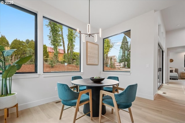 dining room with a notable chandelier, baseboards, and light wood finished floors