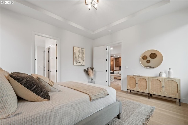 bedroom with a tray ceiling and light wood-style floors
