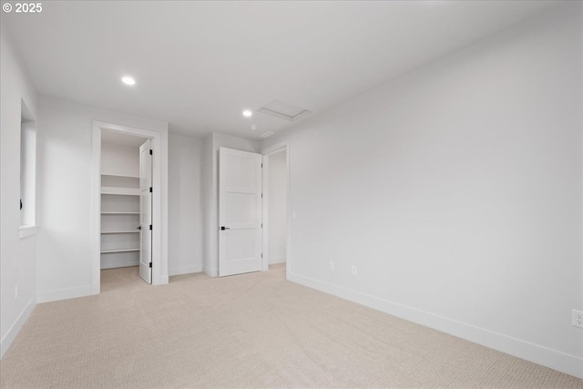 unfurnished bedroom featuring baseboards, attic access, recessed lighting, a spacious closet, and light colored carpet
