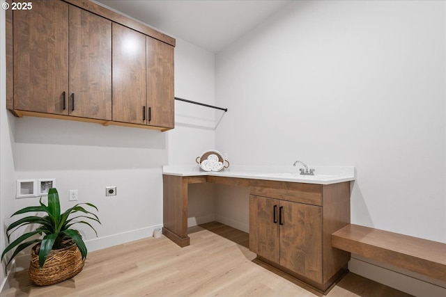 clothes washing area with light wood finished floors, baseboards, cabinet space, electric dryer hookup, and a sink