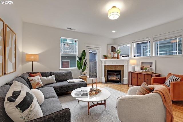 living room featuring a tile fireplace and light hardwood / wood-style floors