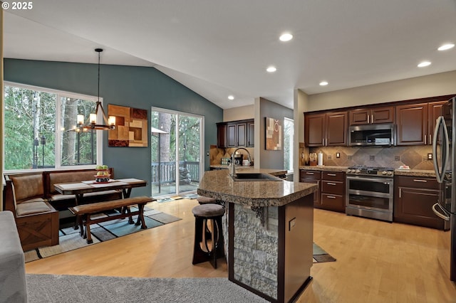 kitchen with dark brown cabinetry, sink, decorative light fixtures, a kitchen breakfast bar, and stainless steel appliances