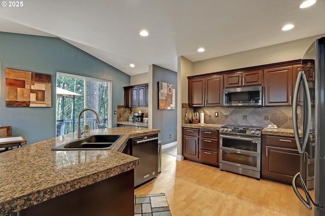 kitchen featuring dark brown cabinetry, lofted ceiling, sink, stainless steel appliances, and decorative backsplash