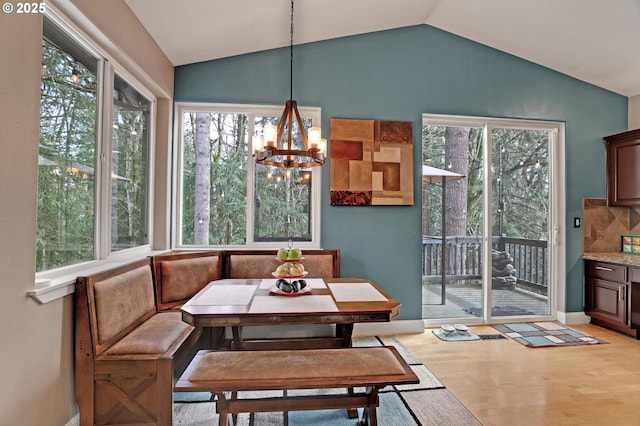 dining room with breakfast area, lofted ceiling, an inviting chandelier, and light wood-type flooring