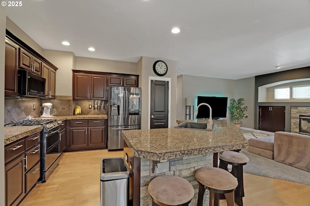 kitchen with appliances with stainless steel finishes, tasteful backsplash, sink, a kitchen breakfast bar, and a center island with sink