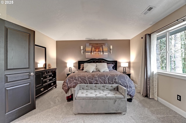 bedroom with light colored carpet and a textured ceiling