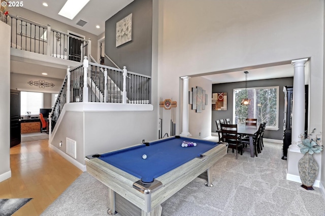 game room featuring decorative columns, plenty of natural light, and a high ceiling