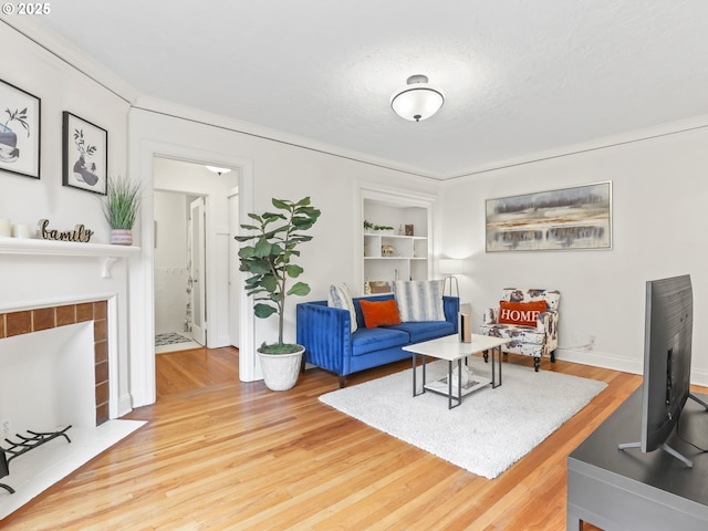 living area featuring built in features, a textured ceiling, wood finished floors, and a tiled fireplace