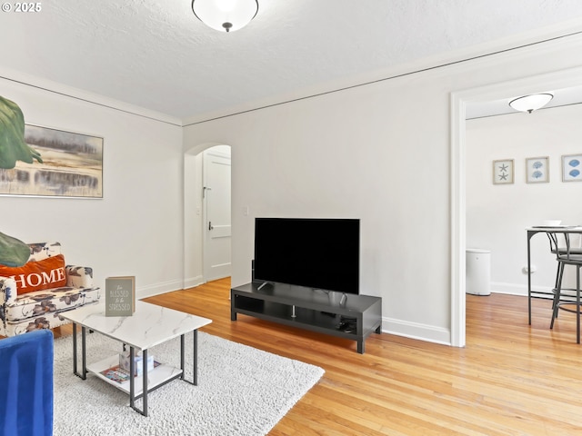 living room with baseboards, arched walkways, a textured ceiling, and wood finished floors