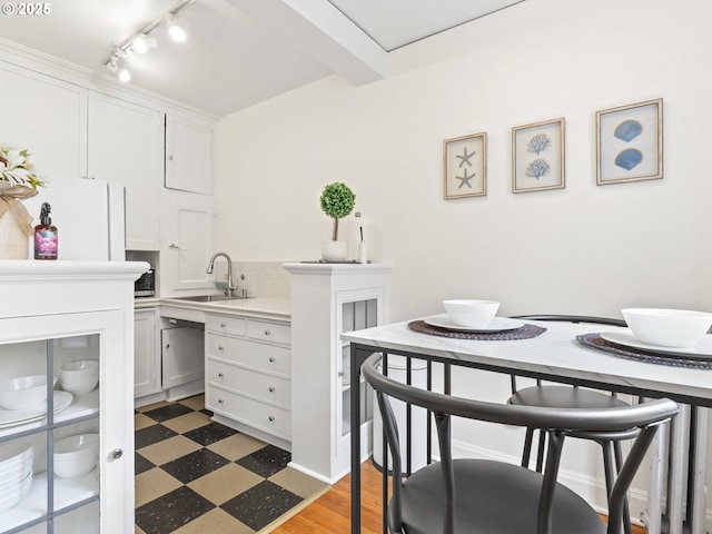 kitchen featuring light floors, light countertops, decorative backsplash, white cabinetry, and a sink