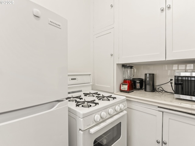 kitchen featuring white appliances, white cabinets, and tasteful backsplash