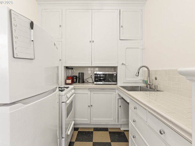 kitchen with white appliances, a sink, white cabinets, tile patterned floors, and backsplash