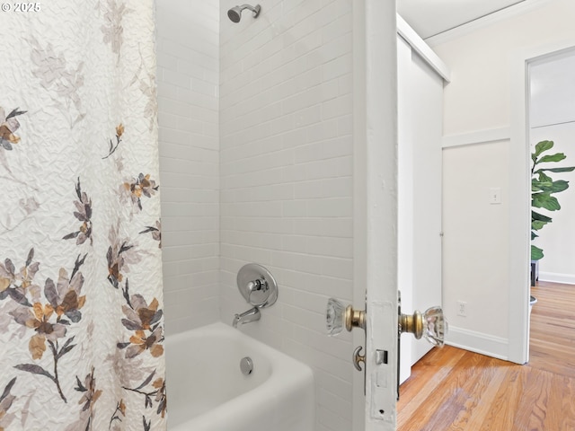 bathroom featuring ornamental molding, shower / tub combo, baseboards, and wood finished floors