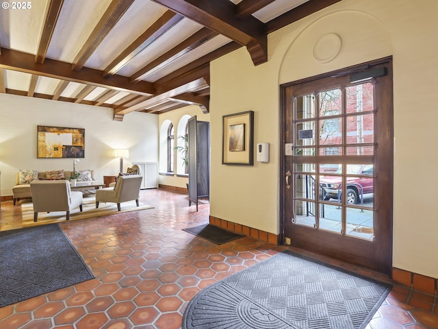 entryway with tile patterned floors, beamed ceiling, baseboards, and arched walkways