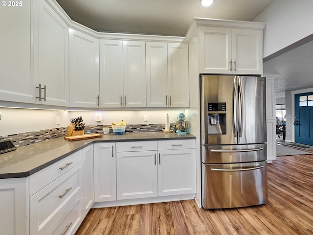 kitchen with stainless steel refrigerator with ice dispenser, light hardwood / wood-style floors, and white cabinets