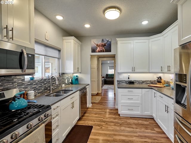 kitchen featuring sink, light hardwood / wood-style flooring, white cabinetry, stainless steel appliances, and a healthy amount of sunlight