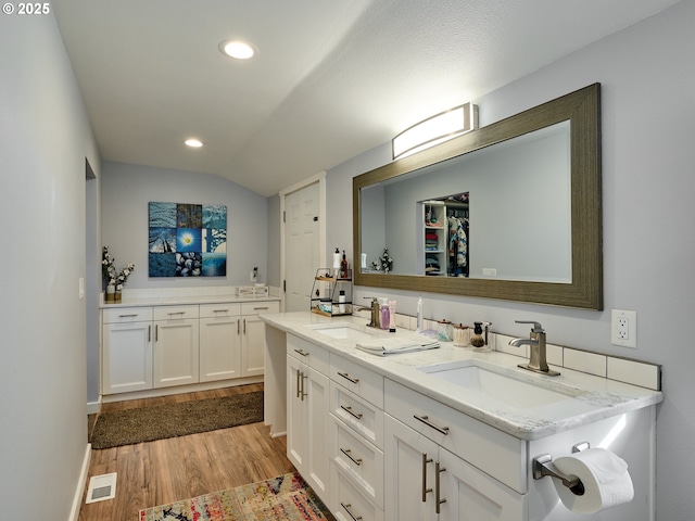 bathroom featuring hardwood / wood-style flooring, vanity, and lofted ceiling