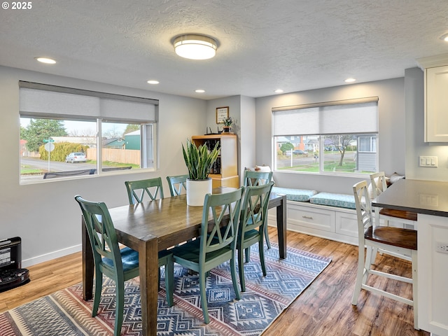 dining space with a textured ceiling, light hardwood / wood-style floors, and a healthy amount of sunlight