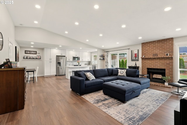 304 SW Birdsdale Dr, Gresham, OR 97080 - living area with light wood-style flooring, lofted ceiling, a brick fireplace, and recessed lighting