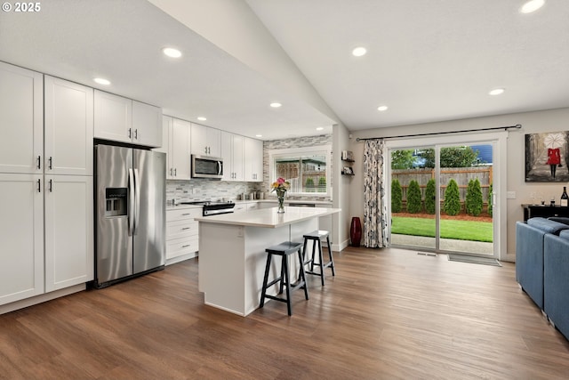 304 SW Birdsdale Dr, Gresham, OR 97080 - kitchen featuring stainless steel appliances, white cabinets, a breakfast bar, dark wood finished floors, and decorative backsplash