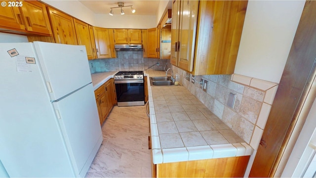 29730 Hillcrest St, Gold Beach, OR 97444 - kitchen featuring freestanding refrigerator, stainless steel range with gas stovetop, a sink, decorative backsplash, and under cabinet range hood