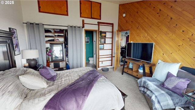 bedroom with a towering ceiling, light carpet, and wooden walls