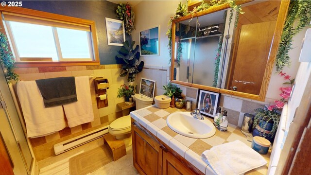 bathroom featuring tile walls, a baseboard heating unit, vanity, toilet, and walk in shower