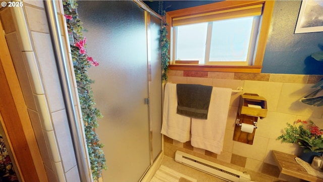 bathroom featuring tile walls, baseboard heating, and walk in shower