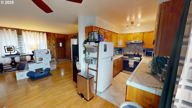 kitchen featuring light hardwood / wood-style flooring, ceiling fan, appliances with stainless steel finishes, tasteful backsplash, and tile countertops