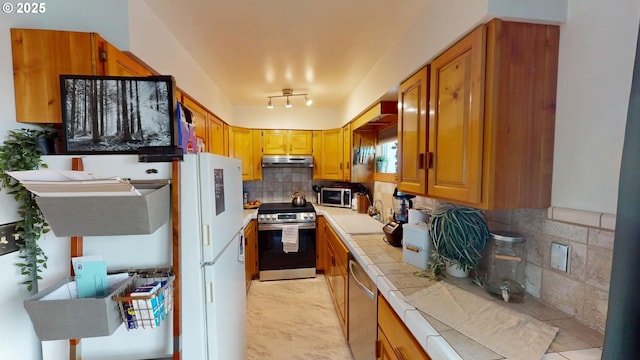 kitchen with tasteful backsplash, sink, tile counters, and stainless steel appliances