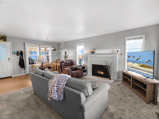 living area featuring a tiled fireplace, carpet floors, healthy amount of natural light, and baseboards