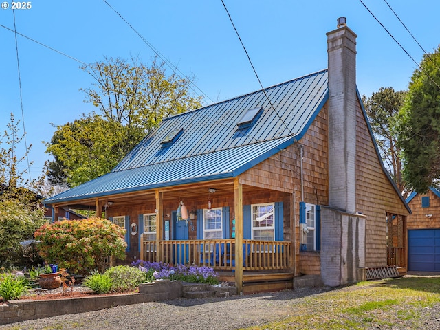 view of front of house with a porch, a standing seam roof, a chimney, and metal roof