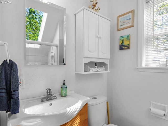 bathroom with plenty of natural light, toilet, and vanity
