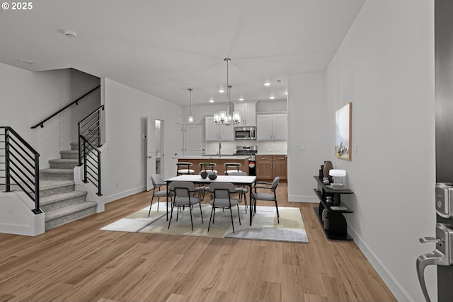 dining area featuring sink, a chandelier, and light hardwood / wood-style floors