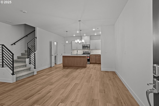 kitchen featuring white cabinetry, a center island, light hardwood / wood-style flooring, pendant lighting, and stainless steel appliances