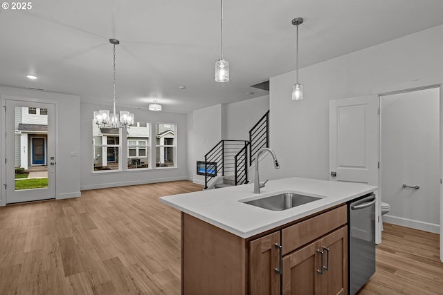 kitchen featuring sink, stainless steel dishwasher, hanging light fixtures, and a center island with sink