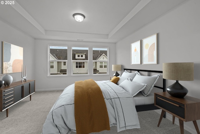 bedroom with light colored carpet and a tray ceiling