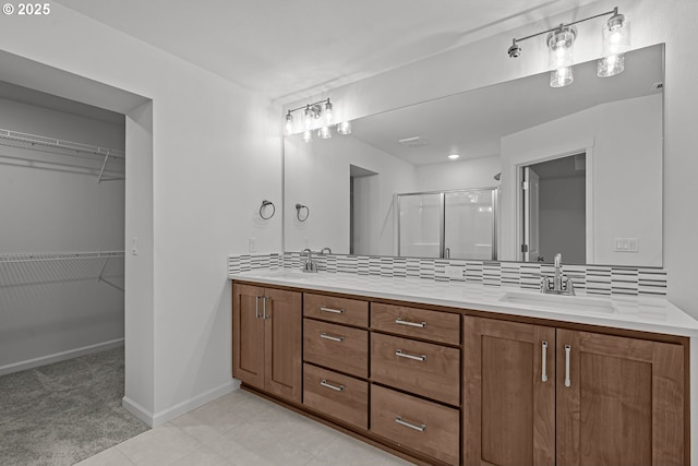 bathroom featuring a shower with door, vanity, and backsplash