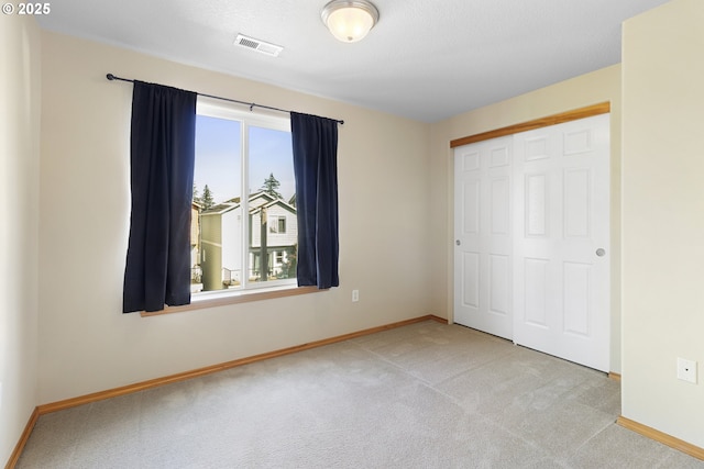 unfurnished bedroom with baseboards, carpet, a closet, and visible vents