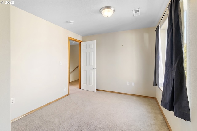 unfurnished room with baseboards, visible vents, and carpet