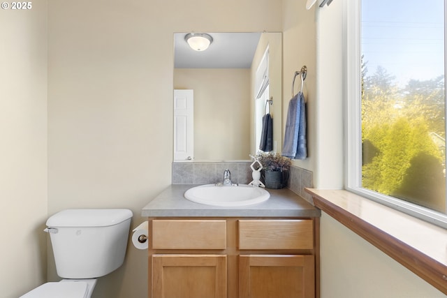half bath with a healthy amount of sunlight, vanity, and toilet