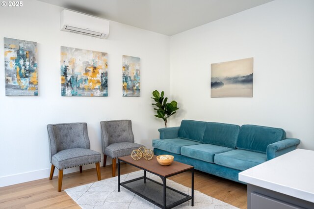 living area featuring an AC wall unit, baseboards, and light wood-style flooring