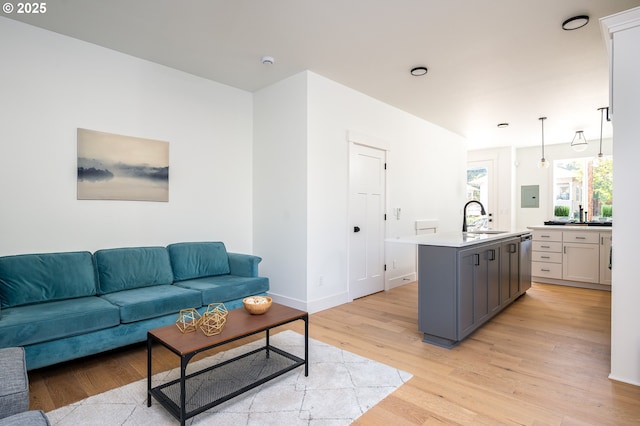 living area with baseboards, electric panel, and light wood finished floors