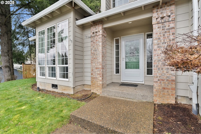 property entrance with a lawn, brick siding, and crawl space