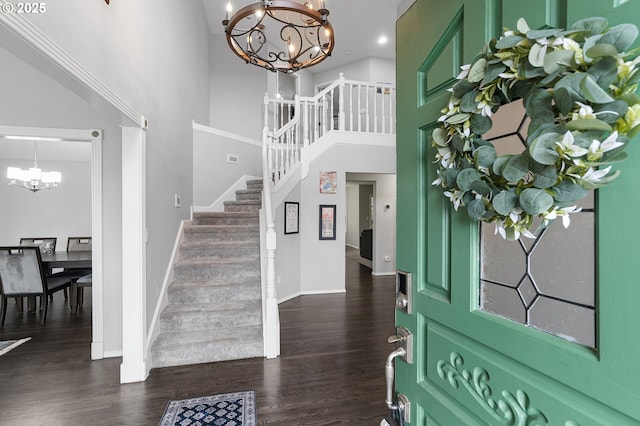 foyer featuring dark wood-type flooring, baseboards, a chandelier, stairway, and a towering ceiling