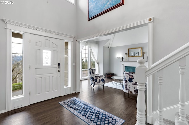 foyer featuring a premium fireplace, stairway, a towering ceiling, and wood finished floors