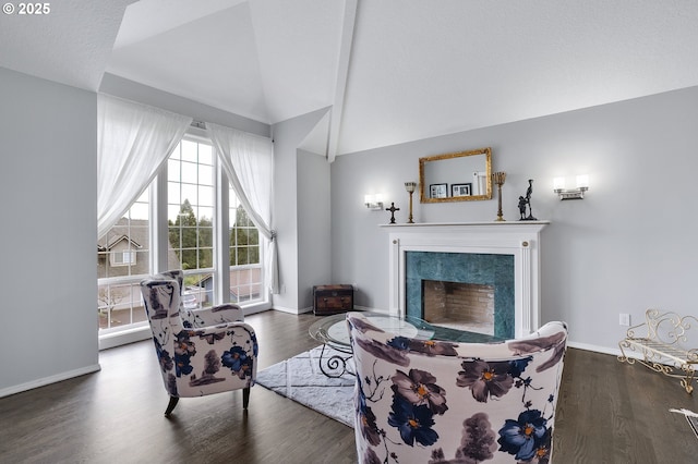 living area featuring a premium fireplace, lofted ceiling, baseboards, and wood finished floors