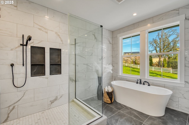 bathroom featuring marble tiled flooring, a soaking tub, walk in shower, tile walls, and recessed lighting
