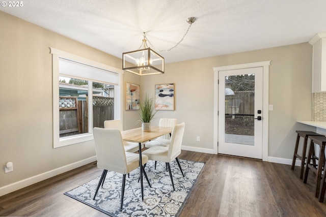 dining area featuring dark wood finished floors, a notable chandelier, and baseboards